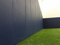 Kodiak Sports Indoor Sports Wood Backed Wall Padding, UV vinyl, green turf floor, and bright lights in facility.